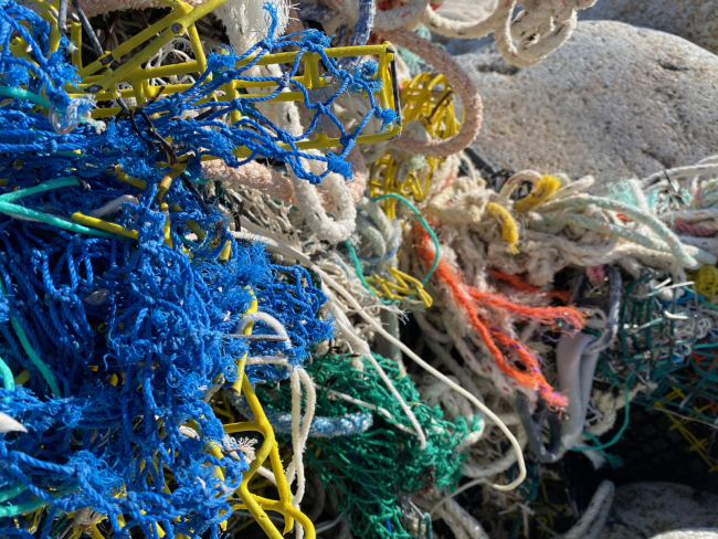 A mass of net, ropes, and other fishing gear on a rocky shoreline.