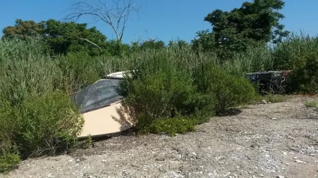 Another abandoned boat flipped over in a marsh.