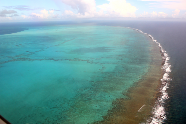 The Northwestern Hawaiian Islands are mostly uninhabited, but still highly afflicted by marine debris. Here, an aerial image shows Midway Atoll’s barrier reef. (Photo Credit: NOAA PIFSC, Coral Reef Ecosystem Program)