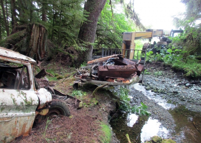 An abandoned vehicle being removed with a forklift from a stream.