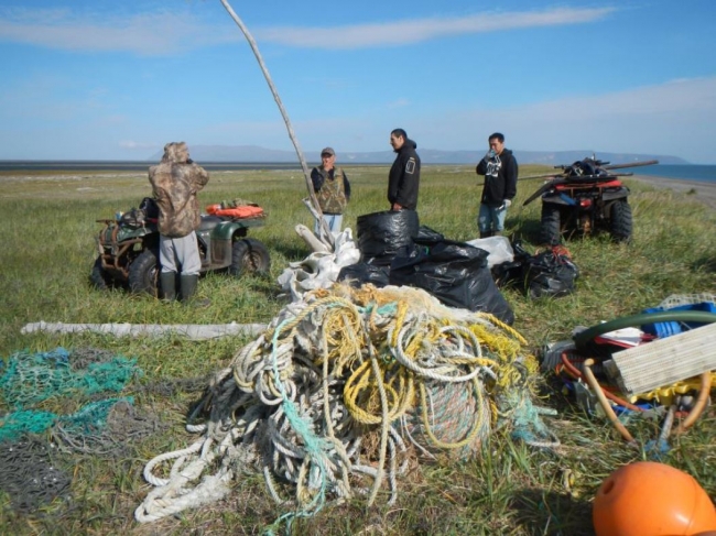 Volunteers around a pile of net and rope debris.