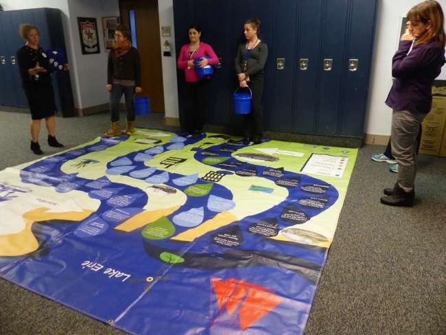 Teachers standing around a watershed floor mat.