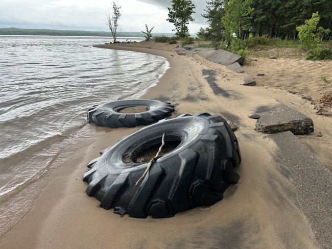 Two tires washed up on a shoreline.