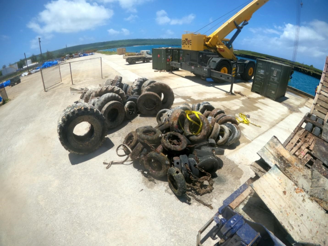 A pile of tires awaits removal at a staging area at a harbor. 