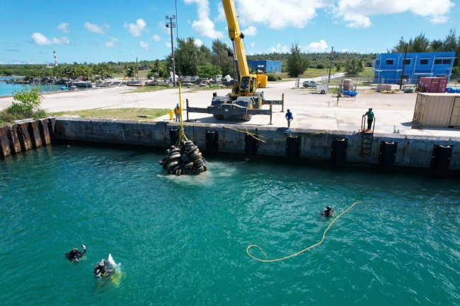 Aerial view of a large pile of tires being lifted out of the sea by a crane. 