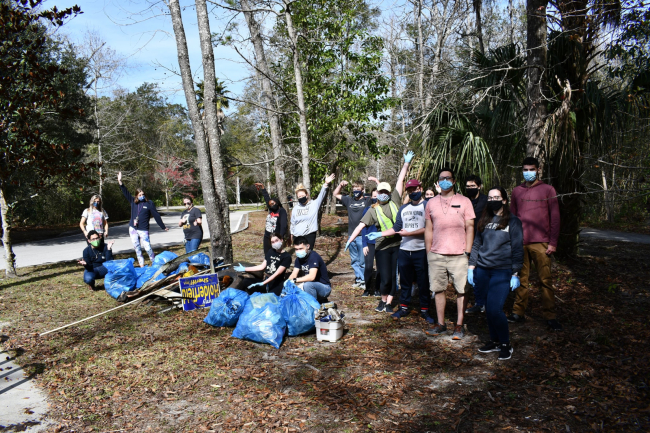 A group of students with bags of debris collected during a park cleanup.