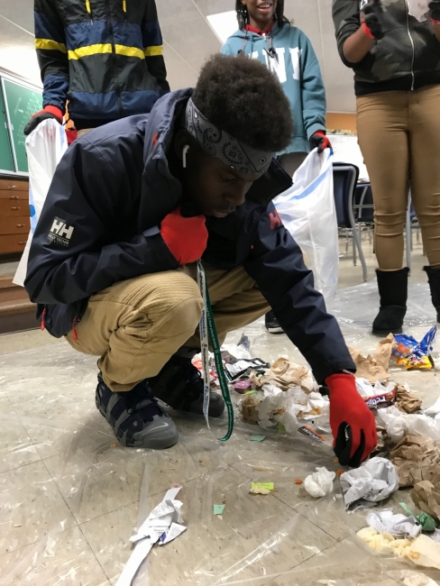 A student bends down to sort collected debris. 