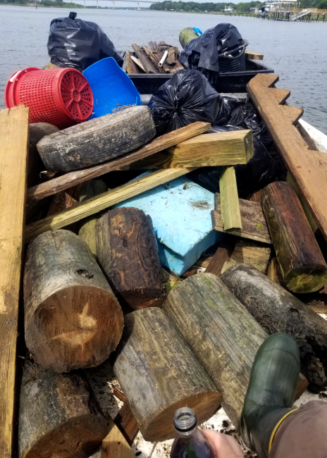 Boat filled with pilings, deck boards, and other dock debris that was collected by a debris crew.