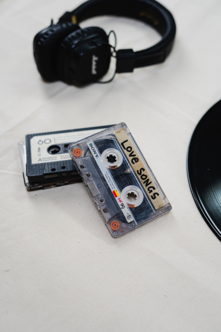 Two cassette tapes on a table with a pair of headphones and a record.