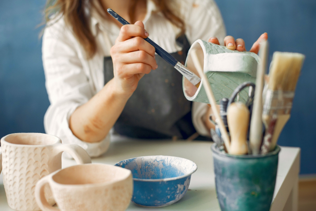 A woman painting pottery.