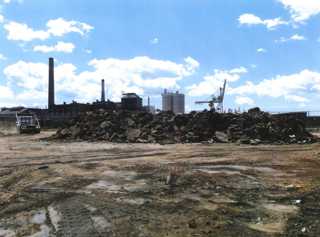 A pile of broken-up cement in front of an industrial site. 