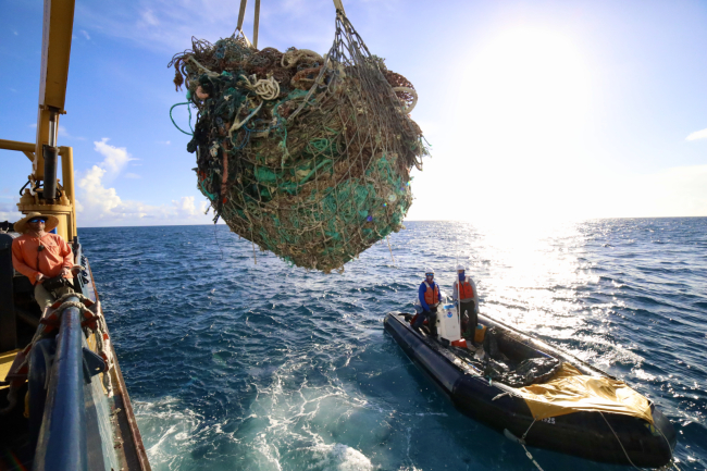 A marine debris removal team member removes offloads 3,190 pounds of derelict fishing net from a boat.