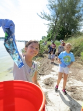 Kids picking up trash on a beach.