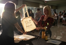 A woman hands a reusable bag over a table to a college student.