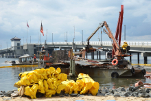 Floats are being utilized to contain random debris, caused by demolition of a home destroyed by Hurricane Sandy, from moving further into Barnegat Bay during the removal process.