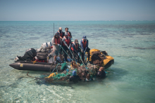 A marine debris removal team pulls a large derelict net mass out of the water.