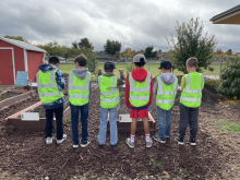 Students stand shoulder to shoulder wearing yellow safety vests. 