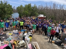 Beach cleanup volunteers pose next to their collected debris. 
