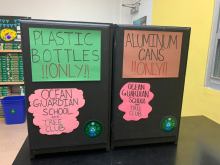 Two recycling bins with student-created signage. 