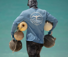 A volunteer carrying derelict fishing buoys off the shoreline.