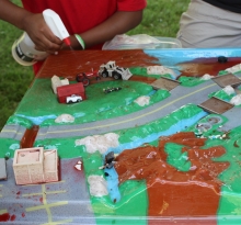 Kid spraying water on a watershed model.