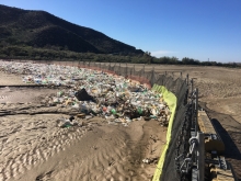 A fence and large weighted boom hold back plastic water bottles and other debris in the Goat Canyon Basin.